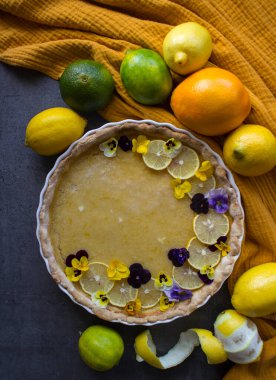 Yabani nonoş çiçekleriyle süslenmiş limonlu turta. Güzel tatlı manzaralı fotoğraf. Kopyalama alanı olan gri arkaplan. 