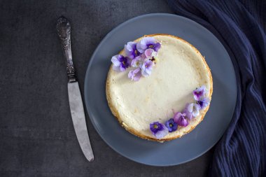Mavi yabani nonoş çiçekleriyle süslenmiş ev yapımı cheesecake. Gri arkaplanda fotokopi alanı ile üstteki görüntü fotoğrafı.  