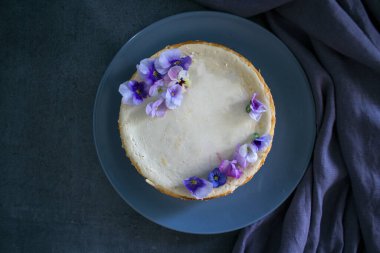 Mavi yabani nonoş çiçekleriyle süslenmiş ev yapımı cheesecake. Gri arkaplanda fotokopi alanı ile üstteki görüntü fotoğrafı.  