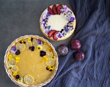 Yenilebilir çiçeklerle süslenmiş limonlu tart ve peynirli kek. Güzel yemek manzaralı fotoğraf. Tatil menüsü fikirleri. 