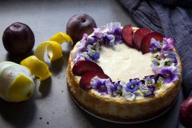 Kırmızı erikler ve yabani nonoş çiçekleriyle süslenmiş cheesecake. Klasik tatlıların en üstteki görüntüsü. 