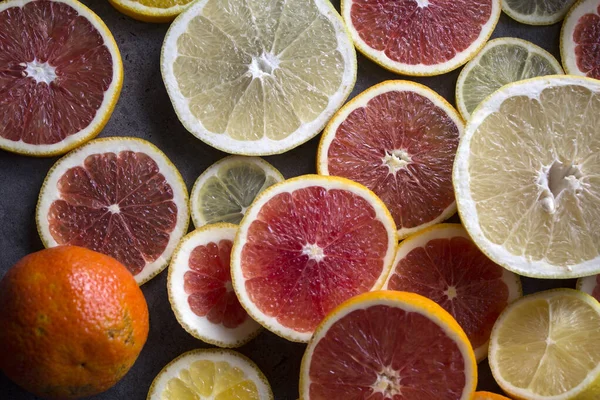 Juicy citrus fruits slices top view photo. Colorful background made of fresh oranges, grapefruits, limes and lemons. Healthy eating concept.