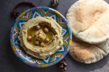 Humus gri masada renkli bir tabakta. Orta Doğu 'nun geleneksel yemekleri. Kopyalama alanı olan karanlık bir arkaplan. Sağlıklı yeme kavramı.