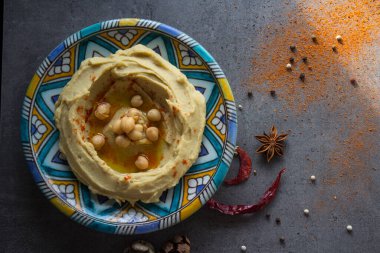 Humus gri masada renkli tabakta. Orta Doğu 'nun geleneksel yemekleri. Kopyalama alanı olan karanlık bir arkaplan. Sağlıklı yeme kavramı. 