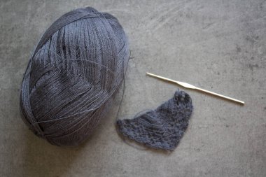 Gri yün yumağı, tığ işi kanca ve kopyalanmış arkaplanda desen. 