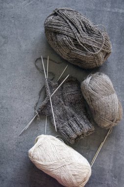 Organik yünden yapılmış sıcak çoraplar ördüm. Kahverengi çorap, örgü iğneleri ve doğal iplik yumağının yakın çekimi. Kopyalama alanı olan gri arkaplan. 