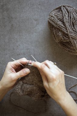Kadın elleri örgü iğnelerini tutuyor. Gri arkaplanda fotokopi alanı olan bir fotoğrafı kapat. Sıcak çorap örüyorum.. 