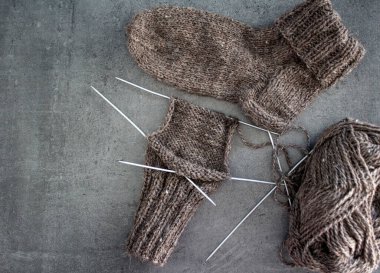 Samimi örgü örüyorum. Gri arka planda kahverengi yün çoraplar. İğne işlemi devam ediyor. Doğal koyun yün çorabı. Yakın çekim fotoğrafı..