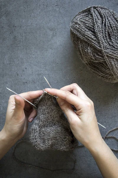 女性手牵着针织针织在灰色背景下与复印空间的近照 织暖袜子 — 图库照片