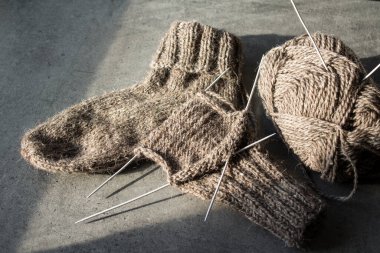 Koyun yününden yapılmış kahverengi çoraplar. Örgü çorapların, iğnelerin ve sıcak iplik yumağının üst görüntüsü. Kış hobileri konsepti.