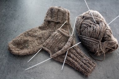 Koyun yününden yapılmış kahverengi çoraplar. Örgü çorapların, iğnelerin ve sıcak iplik yumağının üst görüntüsü. Kış hobileri konsepti.