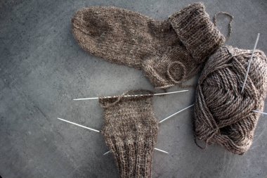 Samimi örgü örüyorum. Gri arka planda kahverengi yün çoraplar. İğne işlemi devam ediyor. Doğal koyun yün çorabı. Yakın çekim fotoğrafı..