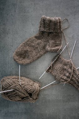Koyun yününden yapılmış kahverengi çoraplar. Örgü çorapların, iğnelerin ve sıcak iplik yumağının üst görüntüsü. Kış hobileri konsepti.