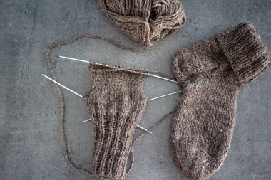 Samimi örgü örüyorum. Gri arka planda kahverengi yün çoraplar. İğne işlemi devam ediyor. Doğal koyun yün çorabı. Yakın çekim fotoğrafı..