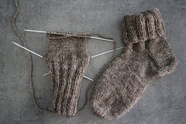 Samimi örgü örüyorum. Gri arka planda kahverengi yün çoraplar. İğne işlemi devam ediyor. Doğal koyun yün çorabı. Yakın çekim fotoğrafı..