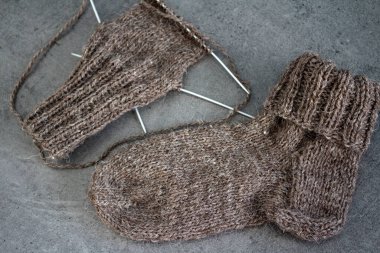 Koyun yününden yapılmış kahverengi çoraplar. Örgü çorapların, iğnelerin ve sıcak iplik yumağının üst görüntüsü. Kış hobileri konsepti.