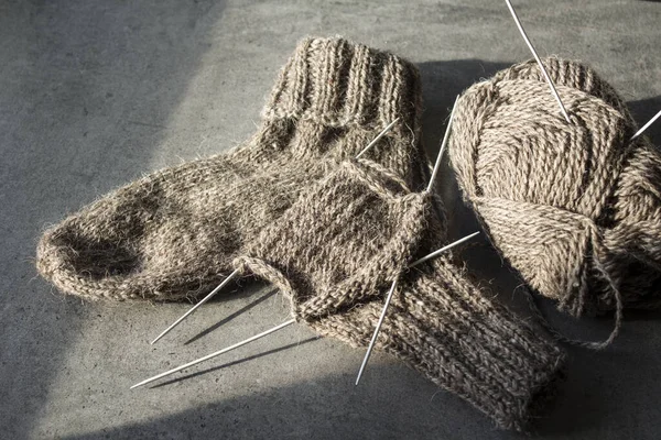 Koyun yününden yapılmış kahverengi çoraplar. Örgü çorapların, iğnelerin ve sıcak iplik yumağının üst görüntüsü. Kış hobileri konsepti.