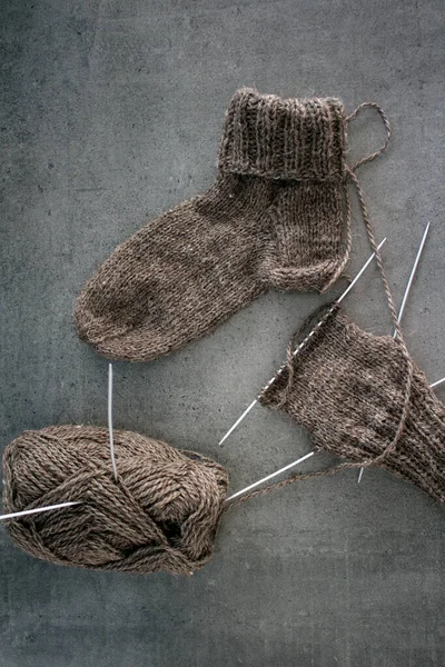 Koyun yününden yapılmış kahverengi çoraplar. Örgü çorapların, iğnelerin ve sıcak iplik yumağının üst görüntüsü. Kış hobileri konsepti.
