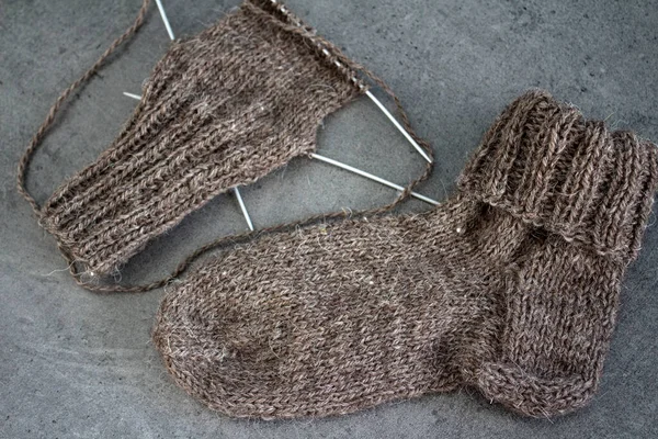 Koyun yününden yapılmış kahverengi çoraplar. Örgü çorapların, iğnelerin ve sıcak iplik yumağının üst görüntüsü. Kış hobileri konsepti.