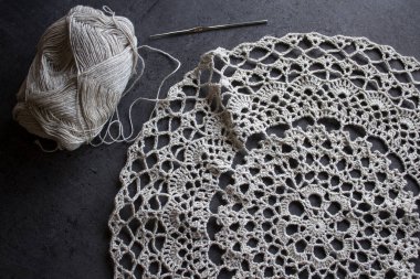 Güzel örgü desenli yakın plan fotoğraf. Organik iplikten yapılmış kırsal stil masa örtüsü. Gri arka plan. Sıcak tığ işi. Gri desenli arka planda güzel keten masa örtüsünün en üstteki fotoğrafı. Hobiler ve el sanatları konsepti.