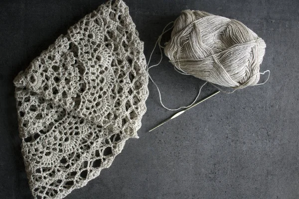 Beautiful crochet pattern close up photo. Rustic style designed table mat made of organic yarn. Gray background. Cozy crocheting. Top view photo of beautiful linen table mat on grey textured background. Hobbies and crafts concept.