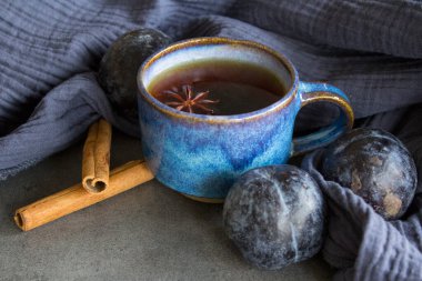 Siyah çay ile mavi seramik bardak ve gri desenli beton masa üzerinde yıldız anason. Taze eriklerle basit kompozisyon..