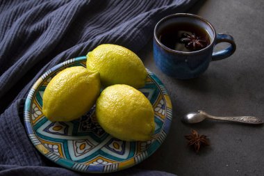 Dekoratif tabakta güzel büyük limonlar. Taze narenciye meyvelerinin üst görüntüsü. Gri desenli arka plan.