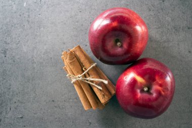 Gri desenli arka planda iki kırmızı elma ve tarçın çubuğu kopyalama alanı ile. 