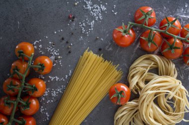 Çiğ makarna, yakın plan fotoğraf. Masada Tagliatellepasta ve kiraz domatesleri. Sağlıklı yeme kavramı.