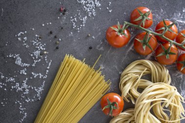 Tagliatelle makarnası, spagetti ve vişneli domatesler gri desenli arka plan. İtalyan yemeği. Üst görüntüdeki taze malzemeler..