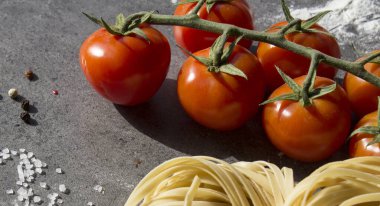 Çiğ makarna, yakın plan fotoğraf. Masada Tagliatellepasta ve kiraz domatesleri. Sağlıklı yeme kavramı.