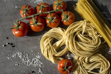 Çiğ makarna, yakın plan fotoğraf. Masada Tagliatellepasta ve kiraz domatesleri. Sağlıklı yeme kavramı.