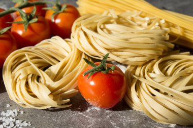 Çiğ makarna, yakın plan fotoğraf. Masada Tagliatellepasta ve kiraz domatesleri. Sağlıklı yeme kavramı.