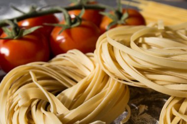 Çiğ makarna, yakın plan fotoğraf. Masada Tagliatellepasta ve kiraz domatesleri. Sağlıklı yeme kavramı.
