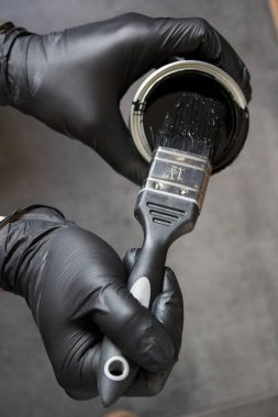 Elinde siyah boya ve fırça tutan adam. Ev yenileme konsepti. Çalışan adamın yakın plan fotoğrafı.. 