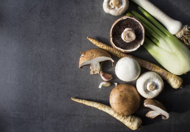 Mevsimlik organik sebzeler, yakın plan fotoğraf. Kahverengi ve beyaz şampiyonlar, rezene, pırasa ve yaban havucu. Gri desenli arka plan ve fotokopi alanı. sağlıklı yeme kavramı.