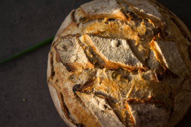Masada taze pişmiş zanaatkar ekmeği. Fotokopi alanı olan koyu gri arkaplan. Ev yapımı ekşi ekmek tarifi..