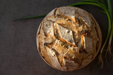 Masada taze pişmiş zanaatkar ekmeği. Fotokopi alanı olan koyu gri arkaplan. Ev yapımı ekşi ekmek tarifi..