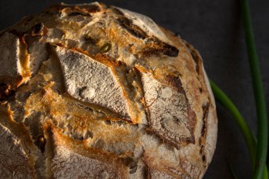 Masada taze pişmiş zanaatkar ekmeği. Fotokopi alanı olan koyu gri arkaplan. Ev yapımı ekşi ekmek tarifi..