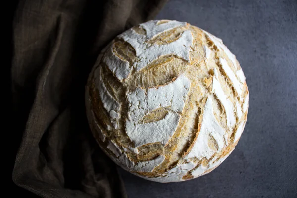 Round sourdough bread close up. Beautiful artisan bread top view photo. Crusty bread on a yellow kitchen towel. Top view photo of fresh baked sourdough bread.