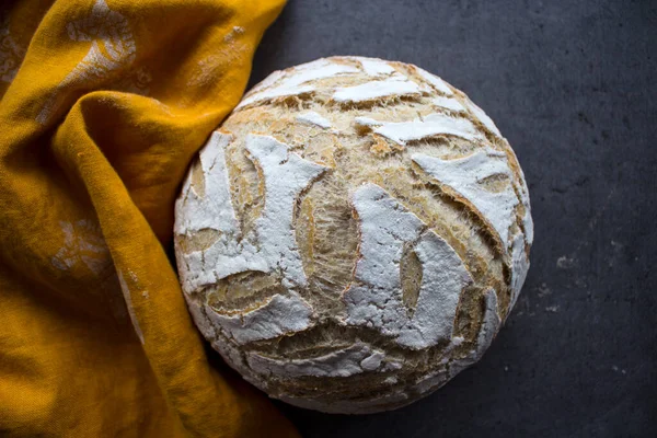 Round whole wheat bread on a table. Yellow fabric background. Top view photo of fresh baked sourdough bread.