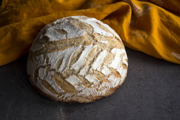 Round whole wheat bread on a table. Yellow fabric background. Top view photo of fresh baked sourdough bread.