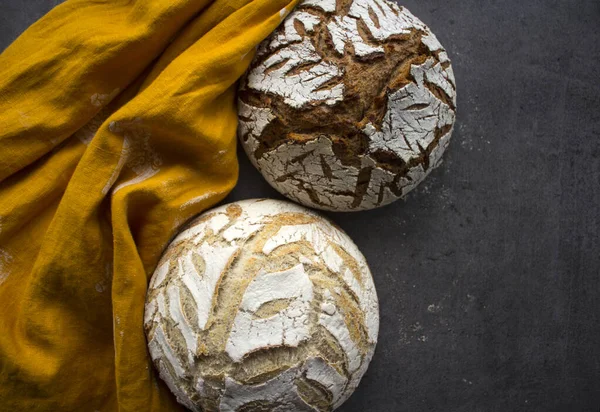 Round whole wheat bread on a table.  Homemade sourdough bread receipts. healthy eating concept. Beautifully scored crusty loaf on gray textured background. Still life food.