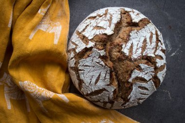 Masada tam buğday ekmeği. Sarı kumaş arka plan. Fırında pişmiş ekşi ekmeğin en iyi görüntüsü..