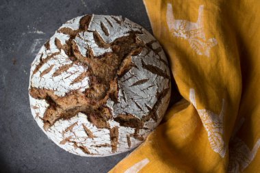 Masada yuvarlak ekşi ekmek. Kabuklu somun dokusu yakın. Taze pişmiş zanaatkar ekmeğinin en üst görüntüsü. Gri desenli arka plan. Sağlıklı yeme kavramı. 