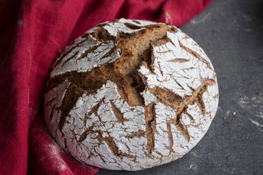 Kırmızı keten havluya çavdar ekmeği. Taze pişmiş zanaatkar ekmeğinin en üst görüntüsü. Gri desenli arka plan ve kopyalama alanı. Sağlıklı yeme kavramı. 