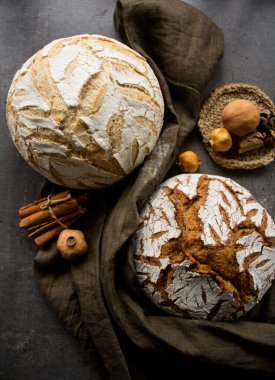 Koyu yeşil keten havlu üzerinde iki zanaatkar ekmek. Güzel çizilmiş ekşi mayalı somun ekmeğinin en üstteki fotoğrafı. Yine de hayat yemeği. Sağlıklı yeme kavramı. 