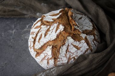 Masada yuvarlak ekşi ekmek. Kabuklu somun dokusu yakın. Taze pişmiş zanaatkar ekmeğinin en üst görüntüsü. Gri desenli arka plan. Sağlıklı yeme kavramı. 