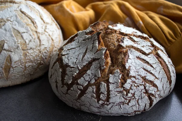 Round sourdough bread on a table. Crusty loaf texture close up. Top view photo of freshly baked artisan bread. Gray textured background. Healthy eating concept.