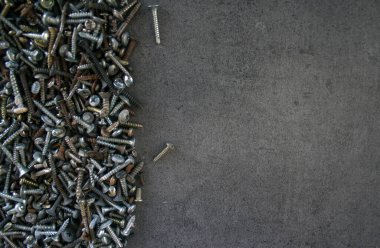 Eski civatalar ve fındıklar koyu gri beton arka planda. Çerçeve ya da sınır. Kopyalama alanı olan desenli arkaplan. 